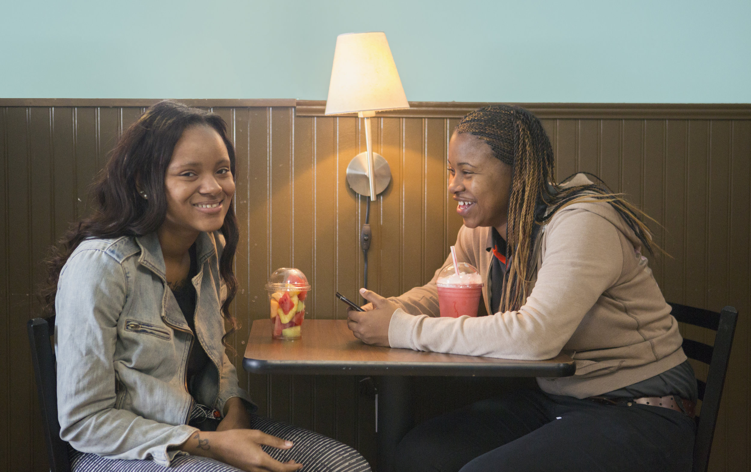 Two young ladies enjoy conversation over food and drink at Community Grounds.